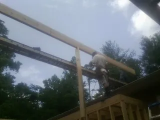 Carpenter setting a ridge beam over a new addition frame — Ice Dam Removal by Roofing Brothers in Kempner