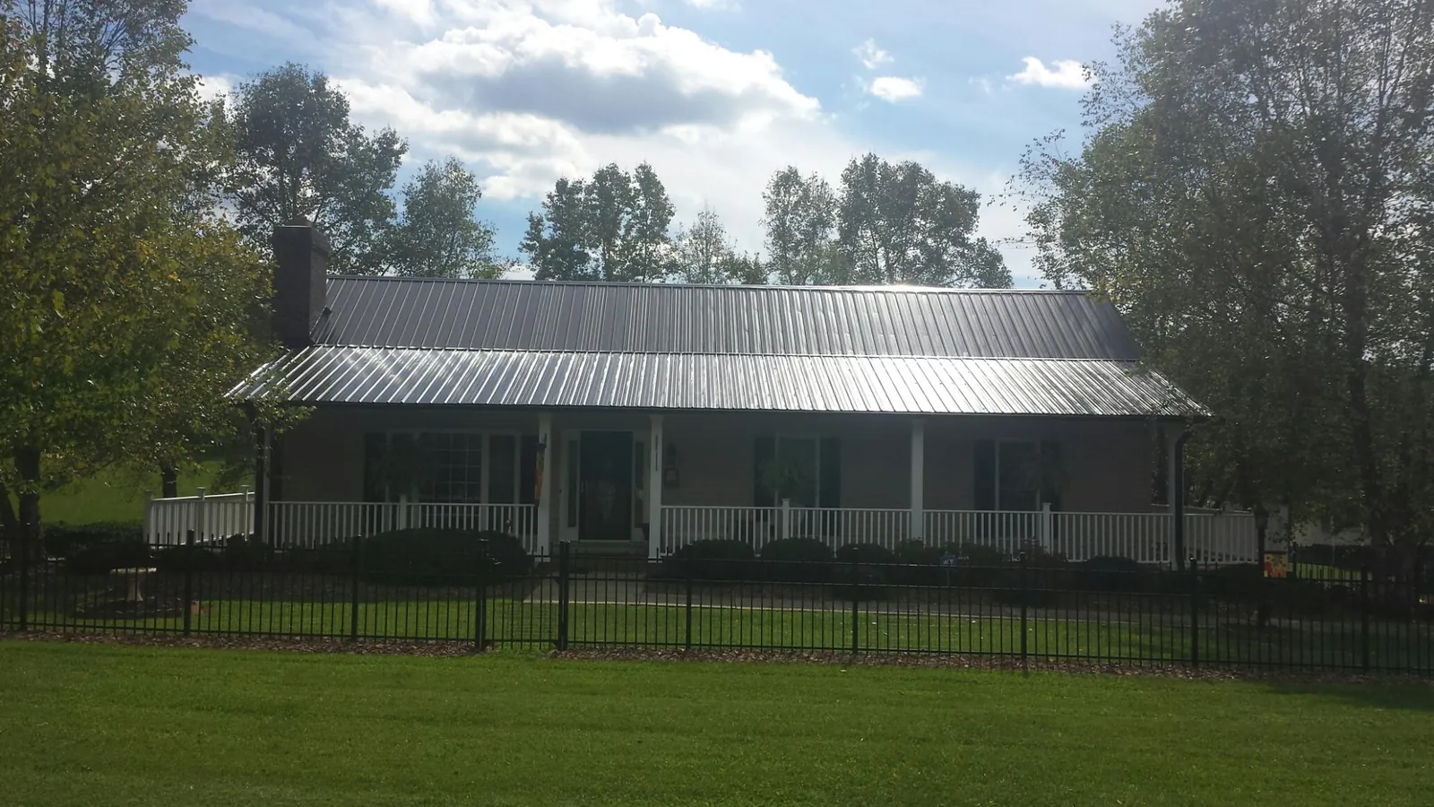 Gray metal roof on a brick ranch with a full width front porch — Gutter Guard Installation work by our crew in Kempner