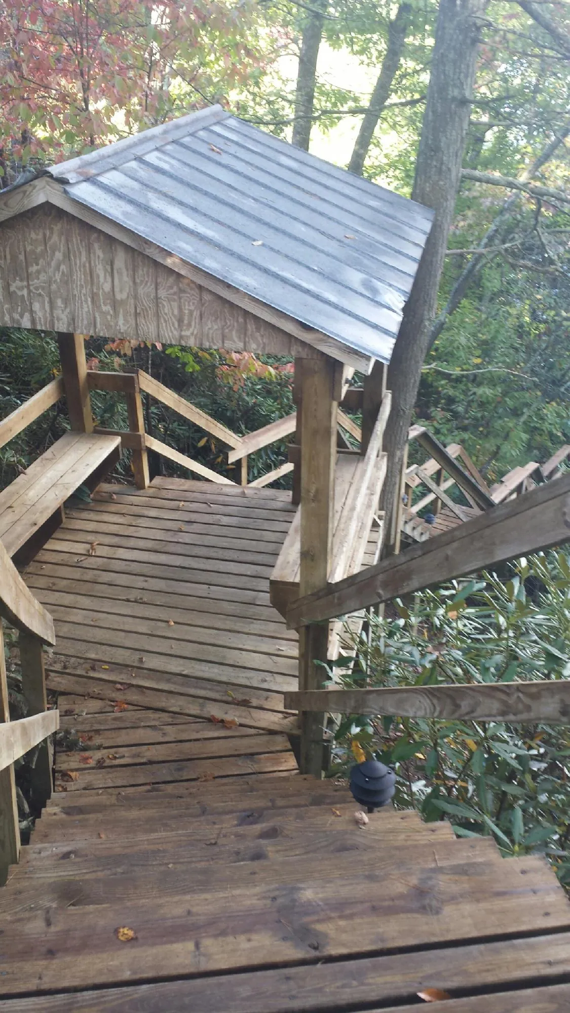 Metal roofed shelter over wooden steps on a wooded walkway — Skylight Repair & Installation work by our crew in Kempner