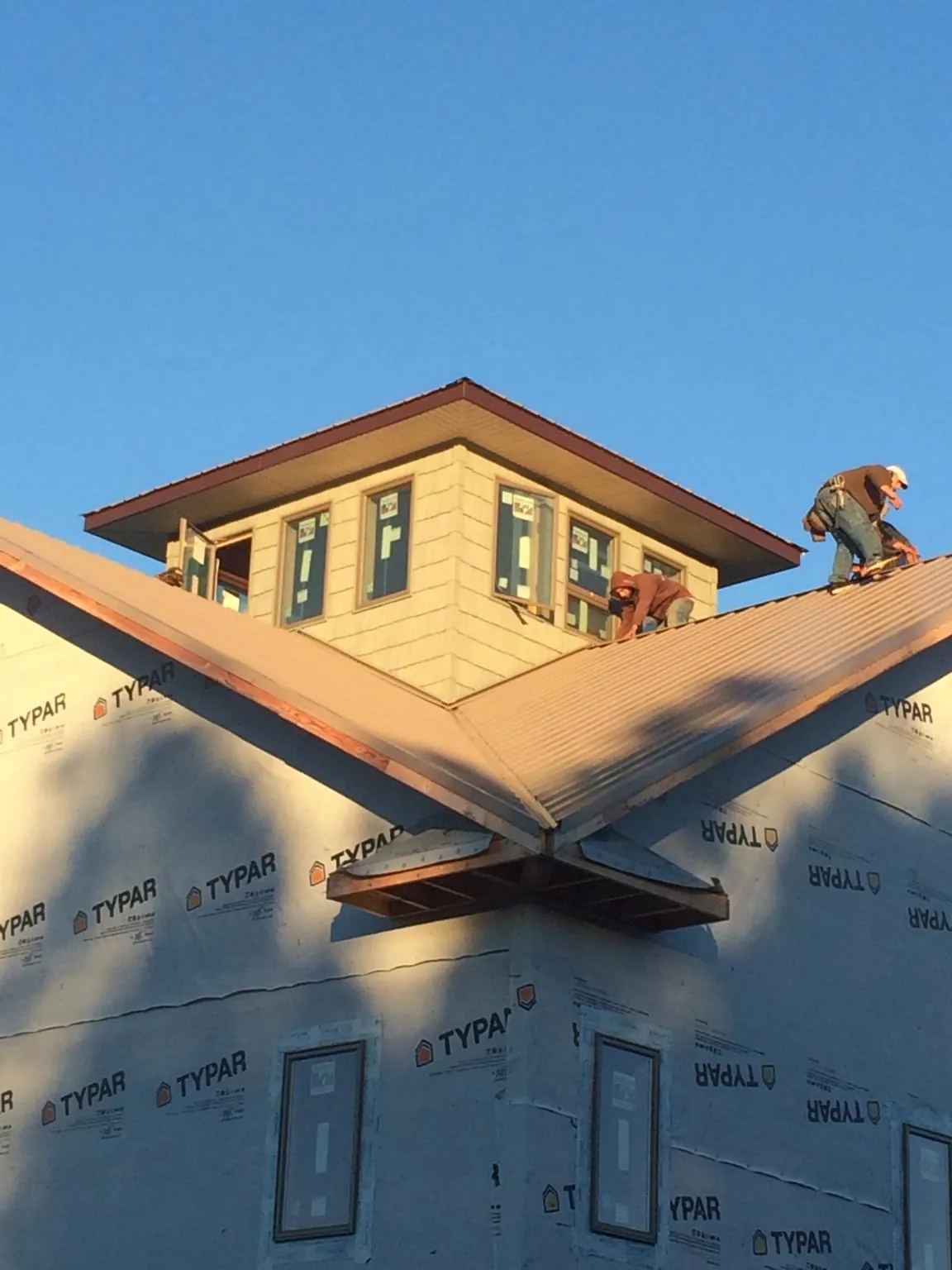 Roofers working around a rooftop cupola on a new metal roof at sunset — Roof Waterproofing in Kempner by Roofing Brothers